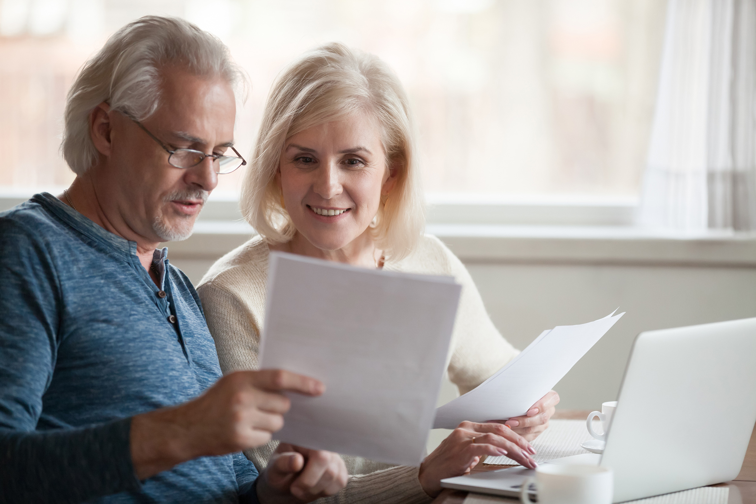A woman smiles as she looks at a stack of papers another person is holding up. Shaffer & Shaffer business and personal injury layers help West Virginians in multiple legal matters.