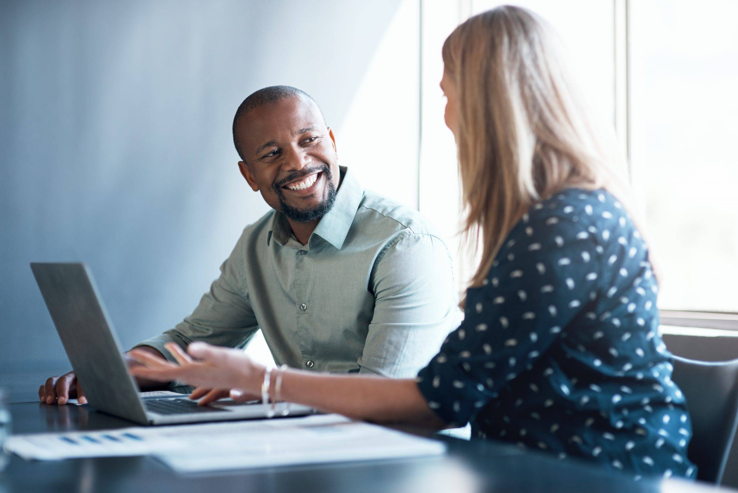 A man in a button-up shirt smiles at a woman as they meet in an office. Shaffer & Shaffer West Virginia lawyers provide personal attention to their clients.