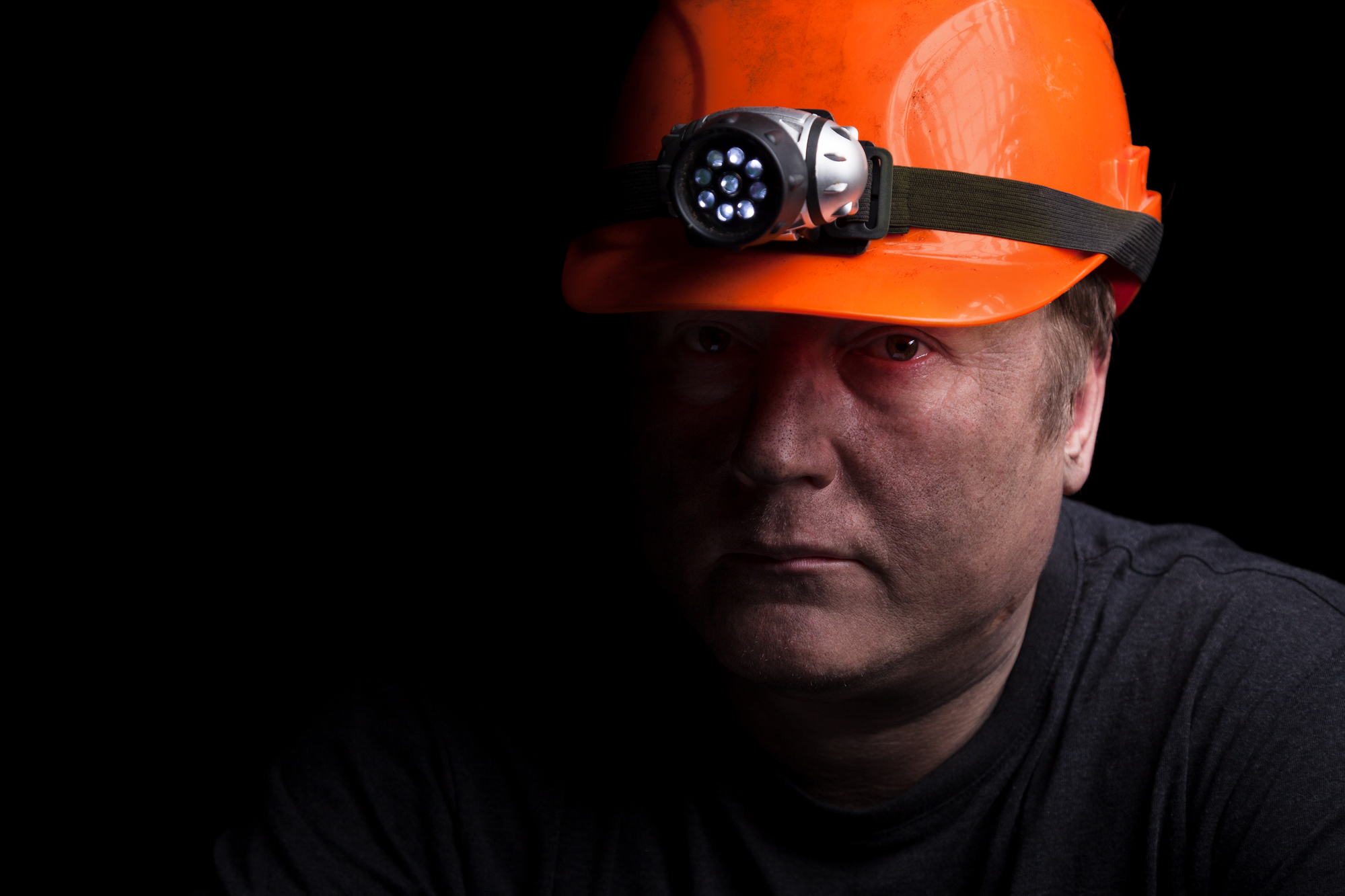 A coal miner wearing a helmet with a headlamp and coal dust on his face. In West Virginia, Shaffer & Shaffer lawyers help miners and other workers after industrial accidents.