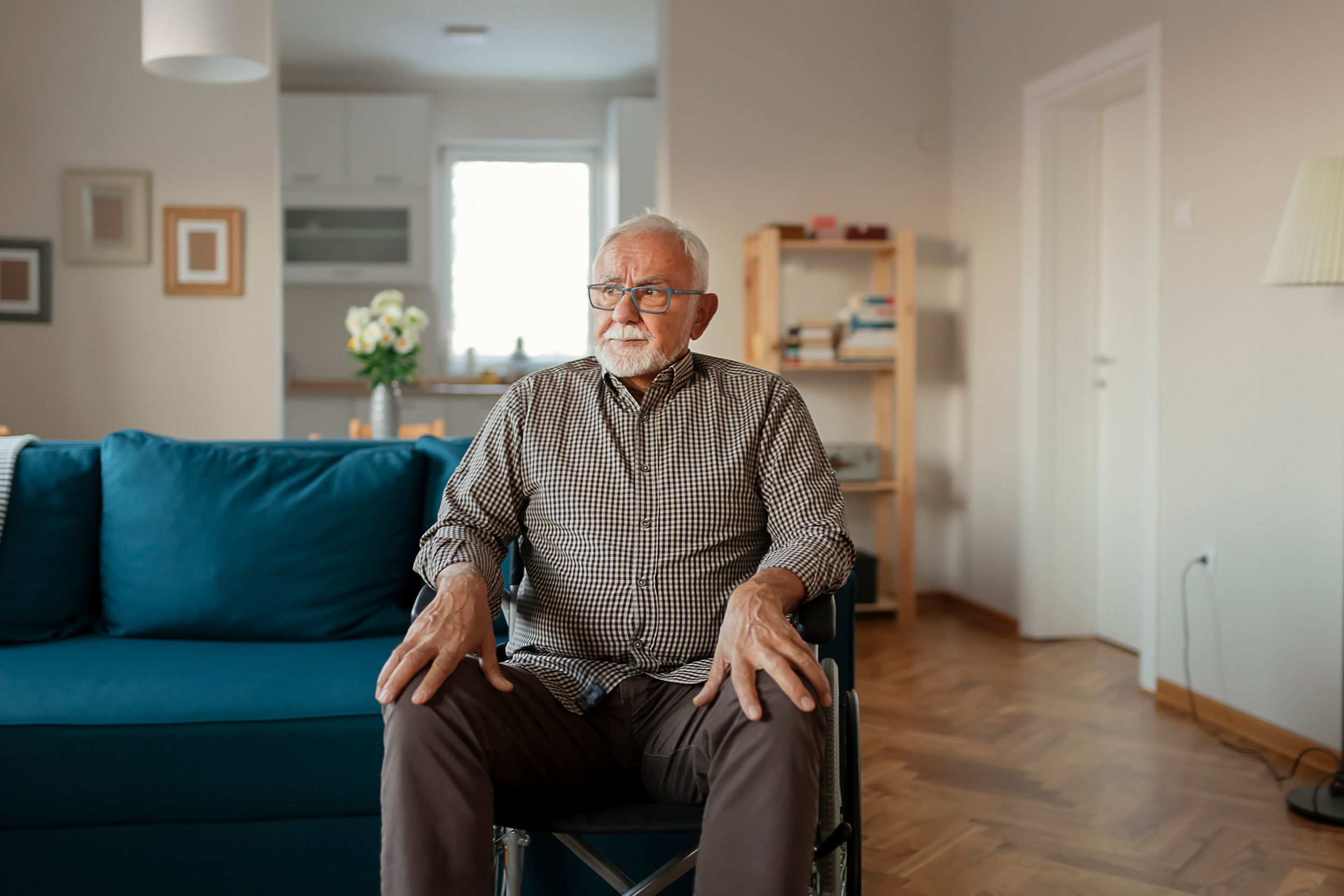 A man sits in a wheelchair in a living room, looking to the side. Nursing home abuse has many causes. Shaffer & Shaffer nursing home neglect lawyers help your family get what's fair.