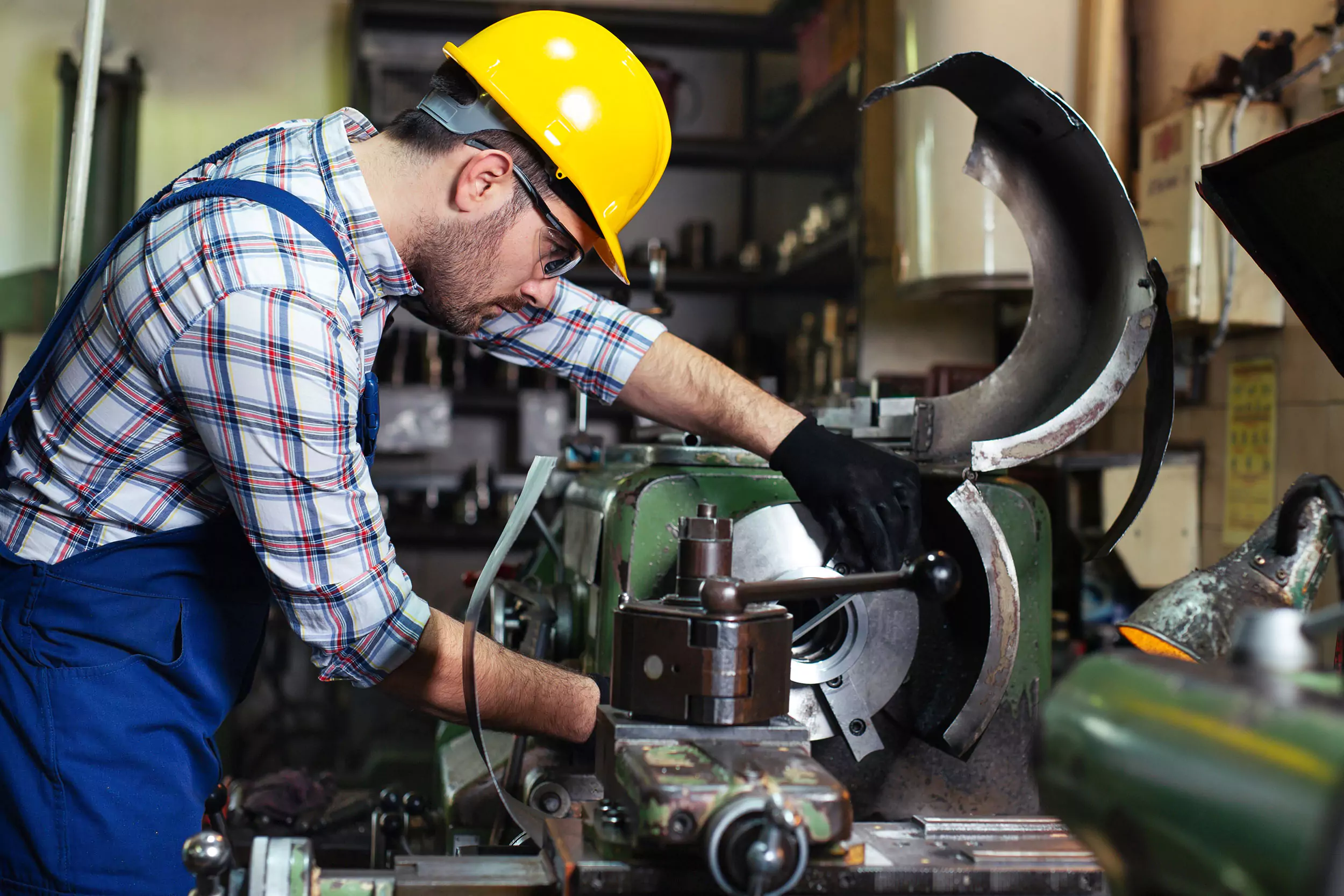 A man in a hard hat works with a shop machine. If faulty equipment at work causes an injury, a Shaffer & Shaffer product liability lawyer can help.