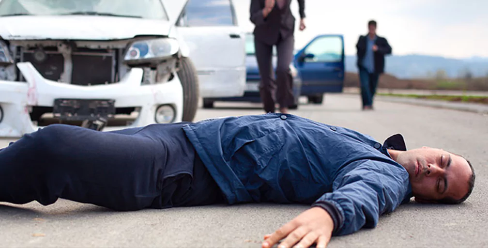 A pedestrian on the ground having been struck by a car.
