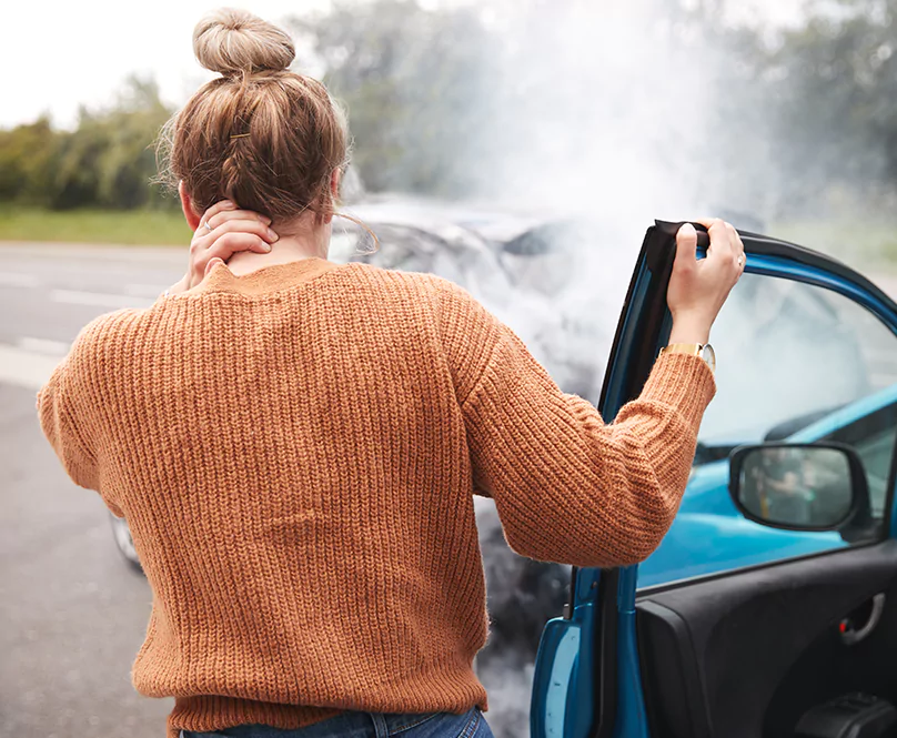 A woman stepping out of her car after just having been in an accident.